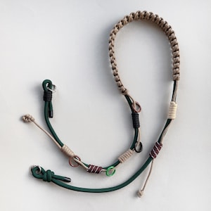 May include: A dog lead and collar set in a variety of colours. The lead has a tan braided handle, with green, tan, and brown accents. The collar has green and tan cords with metal rings and a black clasp. Suitable for small to medium dogs.