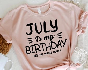 Peut inclure: Un t-shirt à manches courtes rose clair avec le texte noir "JULY Is my BIRTHDAY YES, THE WHOLE MONTH" imprimé sur le devant. Le vêtement présente une encolure ronde et est fabriqué dans un tissu doux, présenté à plat pour une vue claire.