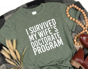 I Survived My Wife's Doctorate Program Shirt,Gift For Husband,Funny PHD Graduation Tee,PHD Dissertation Tshirt,Ironic Shirt,Grad Gag Shirt