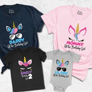 May include: A set of four t-shirts featuring a unicorn design. The shirts are in different colors and have text that says "Daddy of the Birthday Girl", "Mommy of the Birthday Girl", "Lil Bro of the Birthday Girl", and "Emily Birthday Girl 2".