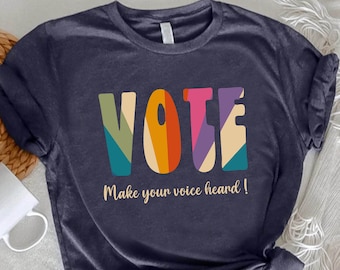 May include: A dark blue t-shirt with a colorful graphic of the word "VOTE" and the text "Make your voice heard!"