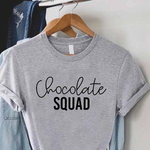May include: Gray t-shirt with the text "Chocolate Squad" in black lettering.