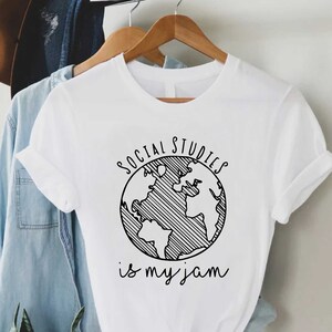 May include: White t-shirt with a black graphic of a globe and the text "SOCIAL STUDIES is my jam".