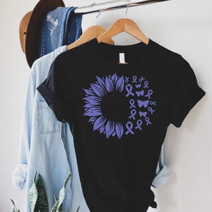May include: Black t-shirt featuring a purple sunflower design. The sunflower is made up of purple ribbons and butterflies.
