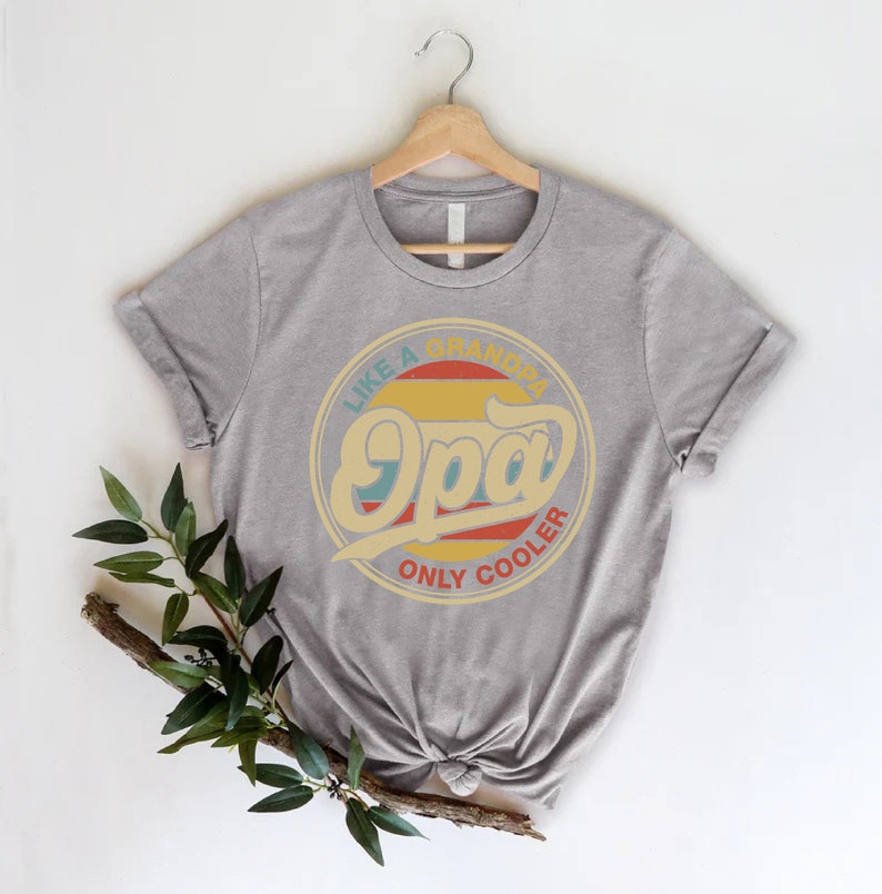 May include: Grey t-shirt featuring a retro-style graphic that reads "Like a Grandpa, Only Cooler" with the word "Opa" in a large, stylised font.