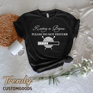 May include: Black t-shirt with white text that reads "Knitting in Progress Please Do Not Disturb" and a graphic of a ball of yarn with knitting needles. The progress bar is filled halfway.
