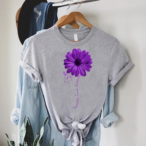 K&ouml;nnte beinhalten: Ein graues T-Shirt mit einer lila Blume und dem Text "Pancreatic Cancer Awareness" auf der Vorderseite.