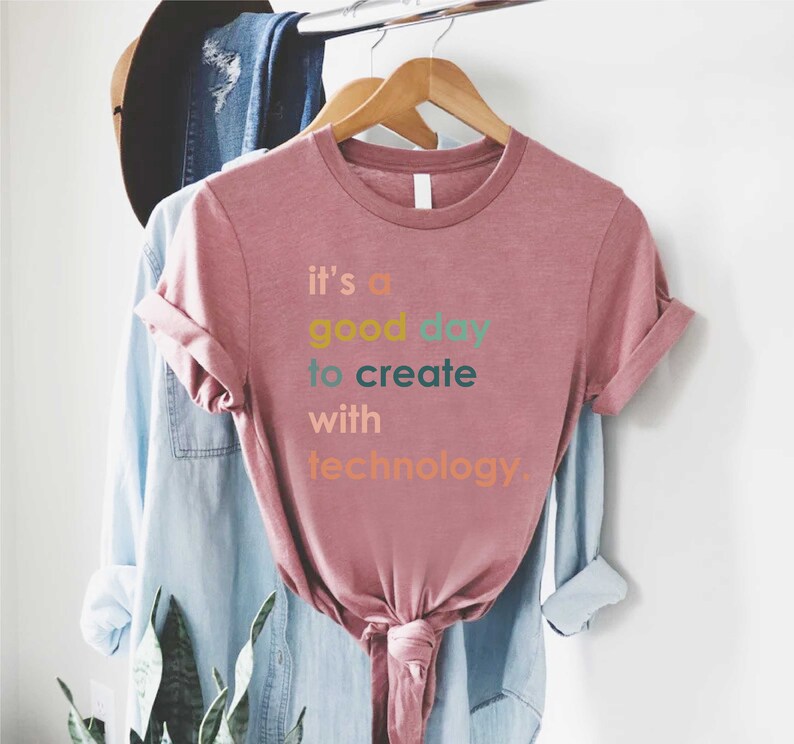 May include: A pink t-shirt with the text "it's a good day to create with technology" in colourful letters.