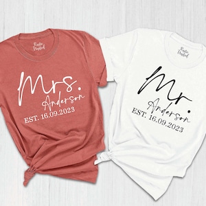 May include: Two t-shirts, one red and one white, with the text "Mrs. Anderson EST. 16.09.2023" and "Mr. Anderson EST. 16.09.2023" printed on them.