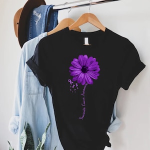 K&ouml;nnte beinhalten: Schwarzes T-Shirt mit einer lila Blume und dem Text "Pancreatic Cancer Awareness".