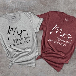 May include: Two t-shirts, one gray and one maroon, with the words "Mr. Anderson EST. 16.09.2023" and "Mrs. Anderson EST. 16.09.2023" printed on them.