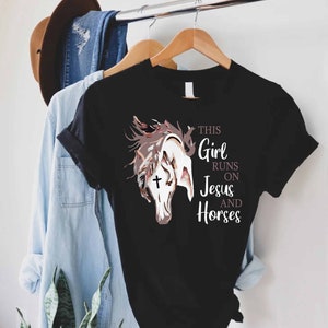 May include: Black t-shirt with a white horse illustration and the text "This Girl Runs On Jesus And Horses".