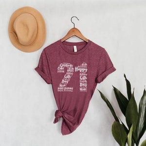 May include: A maroon t-shirt with a white graphic design of the number 22 made up of words related to birthdays, such as "Happy", "Birthday", "Cake", "Friends", and "Gifts".