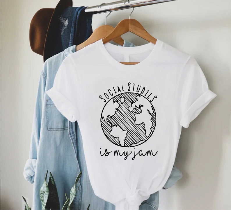 May include: White t-shirt with a black graphic of a globe and the text "SOCIAL STUDIES is my jam".
