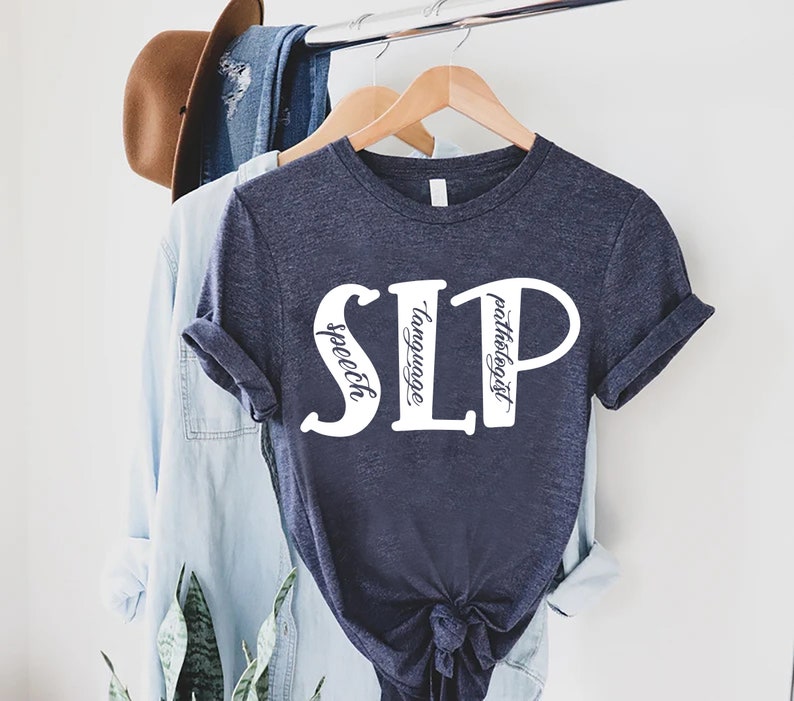 Puede incluir: Una camiseta azul marino con texto blanco que dice "SLP" con las palabras "speech", "language" y "pathologist" escritas verticalmente dentro de las letras.