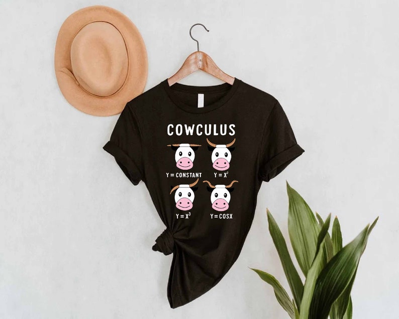 May include: Black t-shirt with a white graphic of cows with math equations. The text "COWCULUS" is at the top of the graphic. The equations are Y = CONSTANT, Y = X, Y = X^2, and Y = COSX.