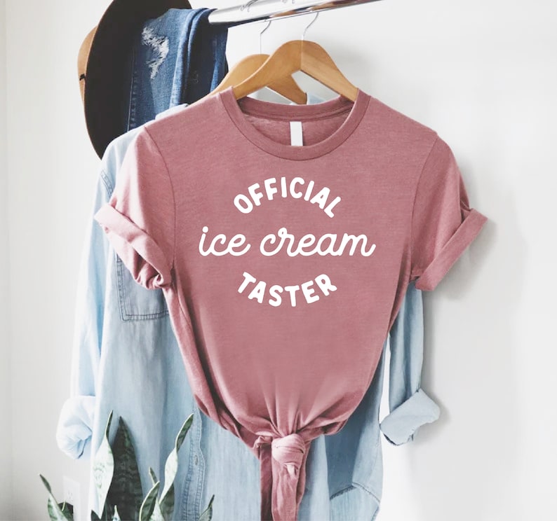 Puede incluir: Una camiseta rosa con el texto "OFFICIAL ice cream TASTER" en blanco.