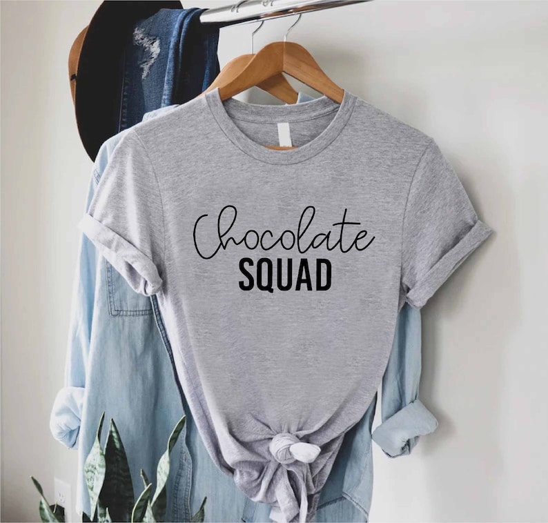 Peut inclure: T-shirt gris avec le texte "Chocolate Squad" en lettres noires.
