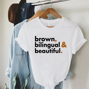 May include: White t-shirt with the text "brown, bilingual & beautiful." printed in black and brown.