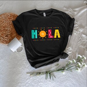 a black t - shirt with the word hola on it