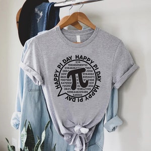 Puede incluir: Una camiseta gris con un gr&aacute;fico negro de un globo de di&aacute;logo que contiene la constante matem&aacute;tica pi, rodeado por los d&iacute;gitos de pi y el texto "Happy Pi Day".