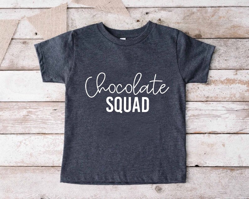 Peut inclure: Un t-shirt gris fonc&eacute; avec le texte "Chocolate Squad" en lettres blanches.