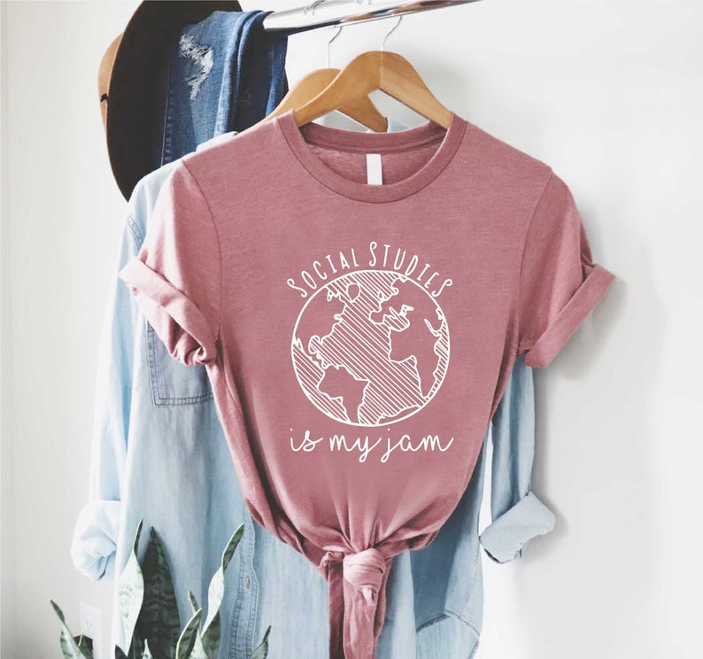 May include: A pink t-shirt with a white graphic of a globe and the text "Social Studies is my jam".
