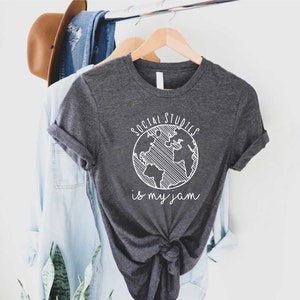 May include: A dark grey t-shirt with a white graphic of a globe and the text "Social Studies is my jam".