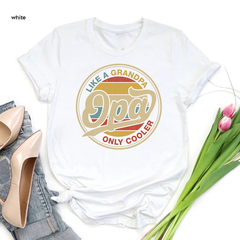 May include: White t-shirt featuring a vintage-style graphic that reads "Like a Grandpa, Only Cooler" with the word "Opa" in a large, stylised font.