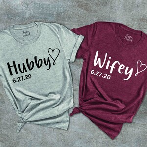 May include: Two t-shirts, one gray and one burgundy, with the words "Hubby" and "Wifey" and a heart design. The date "6.27.20" is printed below each word.