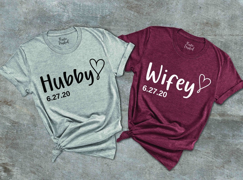 May include: Two t-shirts, one gray and one burgundy, with the words "Hubby" and "Wifey" and a heart design. The date "6.27.20" is printed below each word.
