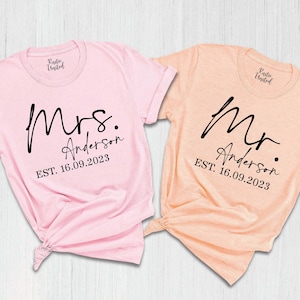 May include: Two pink and peach t-shirts with the words "Mrs. Anderson EST. 16.09.2023" and "Mr. Anderson EST. 16.09.2023" printed on them.