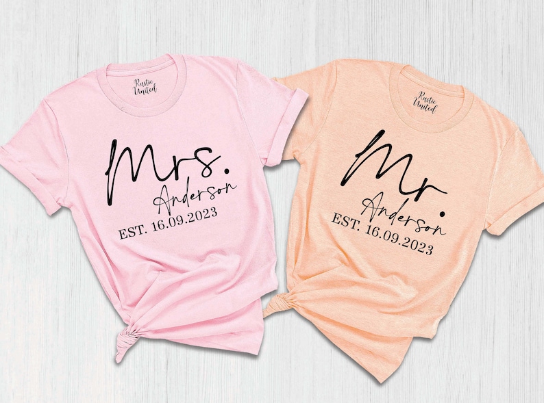 May include: Two pink and peach t-shirts with the words "Mrs. Anderson EST. 16.09.2023" and "Mr. Anderson EST. 16.09.2023" printed on them.