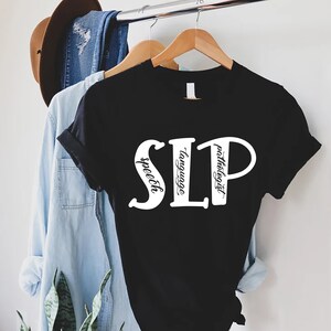 Puede incluir: Camiseta negra con texto blanco que dice "SLP" con las palabras "speech", "language" y "pathologist" escritas verticalmente dentro de las letras.