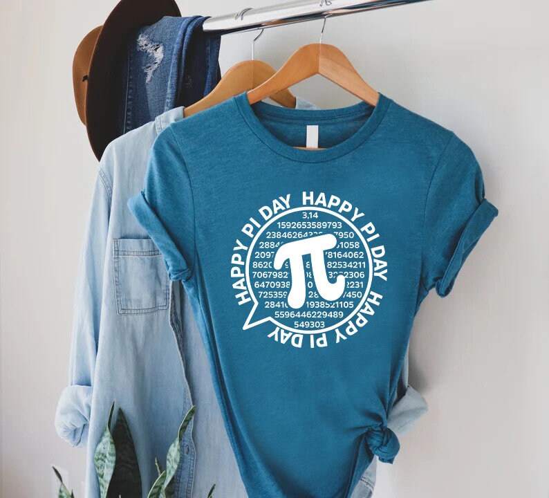Puede incluir: Una camiseta azul turquesa con un gr&aacute;fico blanco de un globo de di&aacute;logo que contiene el texto "Happy Pi Day" y un gran s&iacute;mbolo pi blanco rodeado de los d&iacute;gitos de pi.