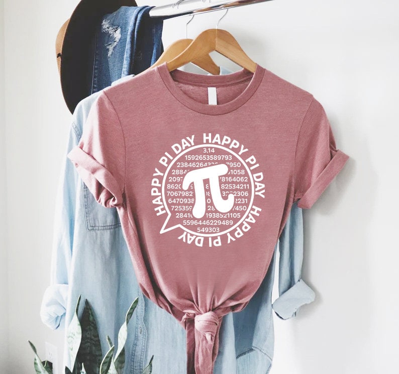 Puede incluir: Una camiseta rosa con un gr&aacute;fico blanco de un globo de di&aacute;logo con el texto "Happy Pi Day" y la constante matem&aacute;tica pi con los primeros 30 d&iacute;gitos.