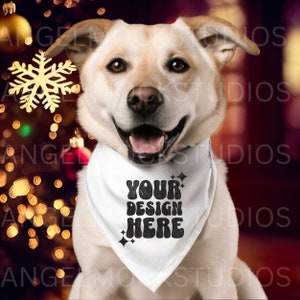 Op de afbeelding: Een witte hond draagt een witte bandana met zwarte tekst die "YOUR DESIGN HERE" zegt in een retro lettertype. De hond zit voor een kerstboom met lichtjes en versieringen.