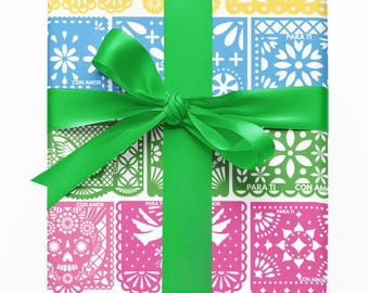 Puede incluir: Una caja de regalo envuelta con papel de estilo papel picado de colores amarillo, azul, verde, rosa y naranja. El regalo está atado con una cinta verde brillante. El papel tiene las frases "Con Amor" y "Para Ti".