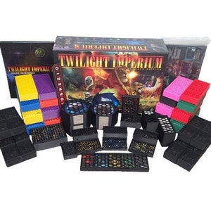 Puede incluir: Un juego de mesa llamado Twilight Imperium: Cuarta Edición con una caja, piezas de juego y dados. Las piezas de juego son negras, rojas, verdes, rosas, amarillas y moradas.
