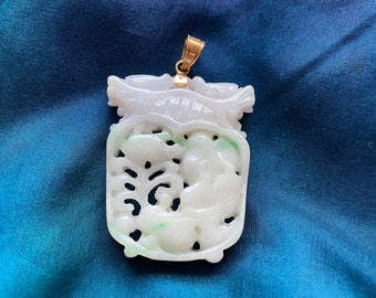 May include: A white jade pendant with intricate carvings of a dragon and floral designs. The pendant is set in gold and has a loop for attaching a chain.
