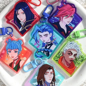 May include: Set of ten colorful keychains featuring anime-style characters. Each keychain is made of clear plastic with a colorful design and a metal ring for attaching to keys or bags.