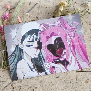 May include: A rectangular art print featuring an anime-style illustration of two characters with dark, heart-shaped facial shadows. One character has dark hair and a white headpiece, while the other has pink hair with bows. The text MarshMeallow is visible.