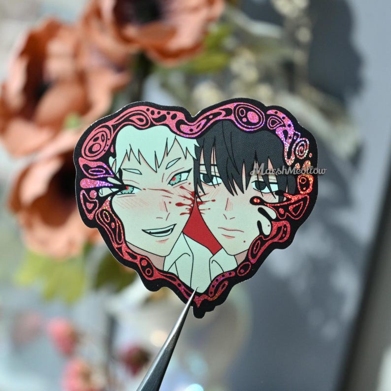 May include: A heart-shaped sticker featuring two anime-style characters. One character has white hair and the other has black hair. Both characters have blood-like markings. The sticker has a pink and red border with the text "MarshMellow".