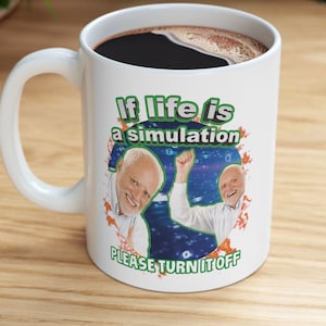 Può includere: Una tazza da caffè in ceramica bianca con un manico nero. La tazza ha una grafica di un uomo con la barba bianca su uno sfondo blu. Il testo sulla tazza recita "If life is a simulation PLEASE TURN IT OFF".