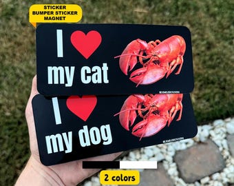 May include: Two rectangular black bumper stickers or magnets. The top sticker features a white letter I, a red heart, the white text my cat, and a red lobster. The bottom sticker features a white letter I, a red heart, the white text my dog, and a red lobster.