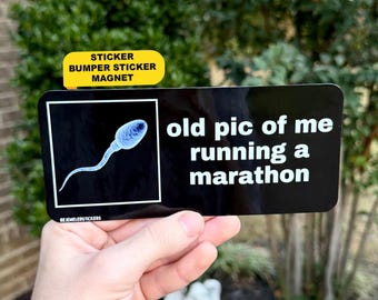 Puede incluir: Una pegatina rectangular negra para parachoques con un gráfico blanco de un espermatozoide dentro de un marco cuadrado y el texto blanco "old pic of me running a marathon". Una pestaña amarilla arriba dice "STICKER BUMPER STICKER MAGNET".