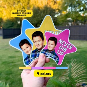 May include: Three star-shaped stickers featuring a photograph of a person wearing a blue and green plaid shirt. The stickers are blue, yellow, and pink, with the pink one displaying the text NEVER GIB UP in bold white capital letters.