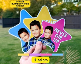 May include: Three star-shaped stickers featuring a photograph of a person wearing a blue and green plaid shirt. The stickers are blue, yellow, and pink, with the pink one displaying the text NEVER GIB UP in bold white capital letters.