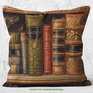 Könnte beinhalten: Ein dekoratives Kissen mit einer Vintage-Illustration eines Bücherregals voller antiker Bücher mit verzierten Einbänden. Die Bücher sind in einer Reihe auf einem Holzregal angeordnet. Das Kissen ist schwarz mit dem Text "Exclusively from SteadyHandPublishing" unten.