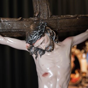 May include: A detailed statue of Jesus Christ on a wooden cross. The figure has a crown of thorns, a beard, and is draped in a white cloth. The cross has the inscription "INRI" at the top. The statue is painted with realistic skin tones.